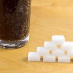 glass of soda next to sugar cubes